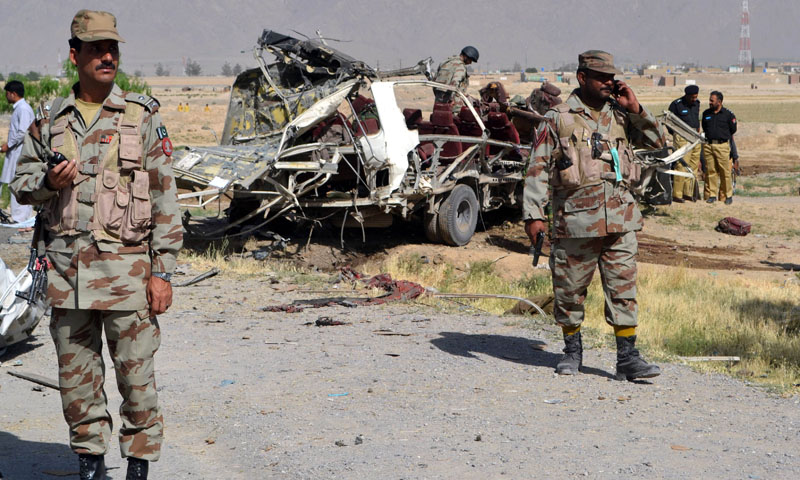 Pakistani security officials keep watch near a destroyed vehicle used by security forces following a bomb attack on the outskirts of Quett, on May 23, 2013.