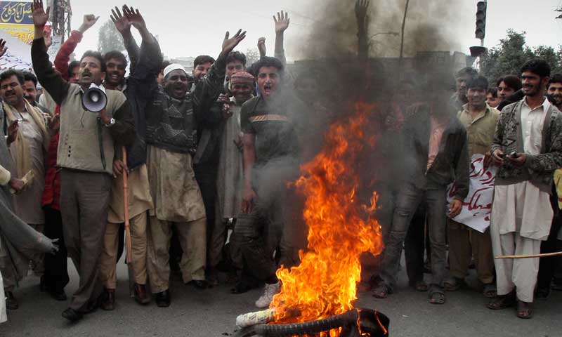 Angry traders and workers chant slogans next to burning tires during a demonstration against long hours breakdown of natural gas and electricity. — Photo by AP