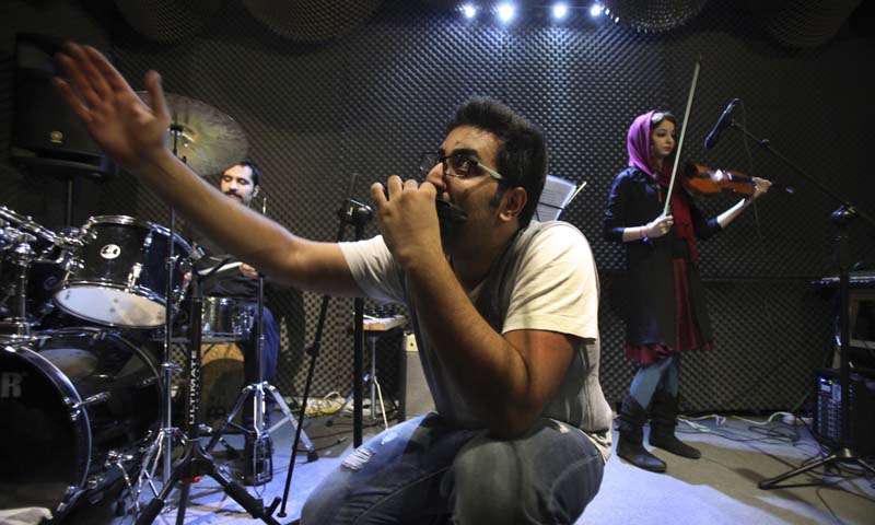 Iranian musician Danial Izadi performs with his harmonica in an unauthorized stage performance for his band called "Accolade" in Tehran, Iran.