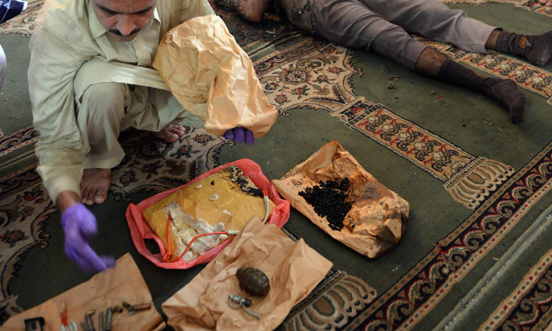 A police official displays explosives next to the body of the suicide bomber at the mosque on the outskirts of Islamabad on August 9, 2013.—AFP Photo