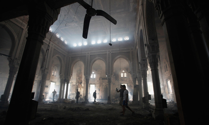 People walk inside the burnt Rabaa Adawiya mosque, the morning after the clearing of a protest which was held around the mosque.