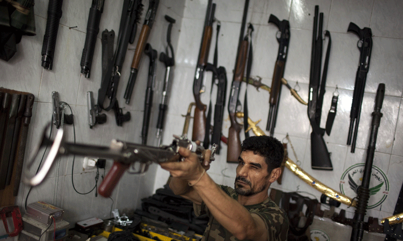 Abu Mohammad checks an AK47 at his gun shop in the Fardos district of Syria's northern city of Aleppo - Photo by AFP