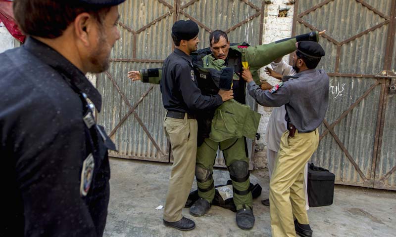 A technician from Pakistan's top bomb disposal unit is helped into his protective suit during a bomb search operation in Peshawar October 2, 2013. — Photo Reuters
