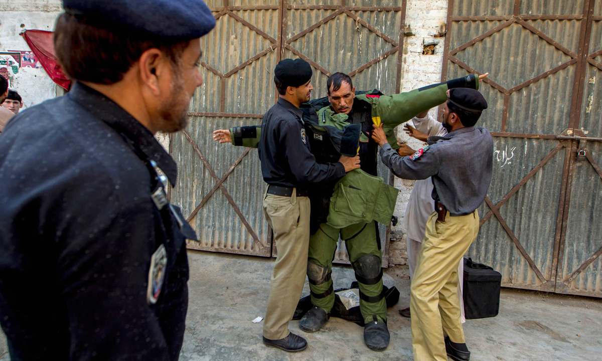 A technician from Pakistan's top bomb disposal unit is helped into his protective suit during a bomb search operation in Peshawar. &ndash; Photo by Reuters