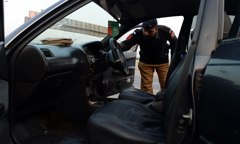 Police officials examine the bullet-riddled vehicle of ASWJ leader Maulana Shamsur Rehman Muavia after an attack by gunmen in Lahore on December 6, 2013.—AFP Photo