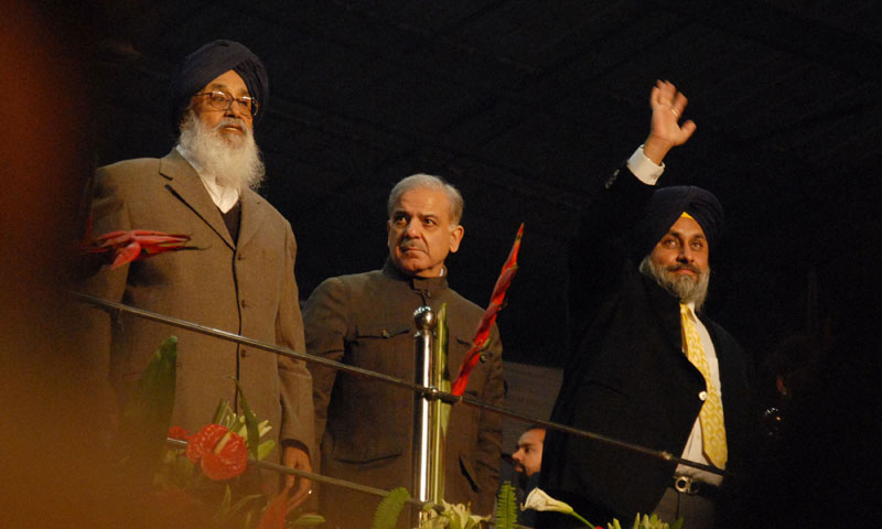 Punjab Chief Minister Shahbaz Sharif (C), Indian Punjab Chief Minister Prakash Singh Badal (L) and deputy Chief Minister Sukhbir Singh Badal greet the crowd during the final match of fourth World Cup Kabaddi Punjab 2013 tournament in Ludhiana. — Photo by AFP