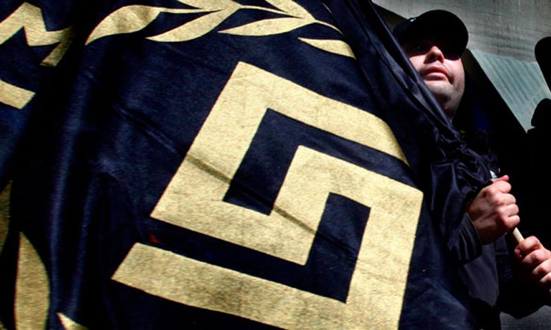 A member of the extreme right Golden Dawn party holds a flag bearing their party's logo during an election campaign rally in Athens. - File Photo