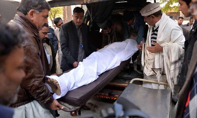 Volunteers and relatives move the body of victim of a suicide bomb attack, at a hospital in Rawalpindi on January 20, 2014. — Photo by AFP