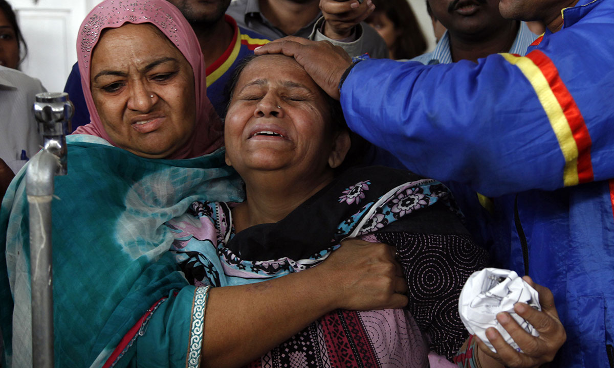 People comfort a woman whose son who was killed by unknown gunmen in Karachi, Pakistan, Tuesday, Jan. 21, 2014. – Photo by AP