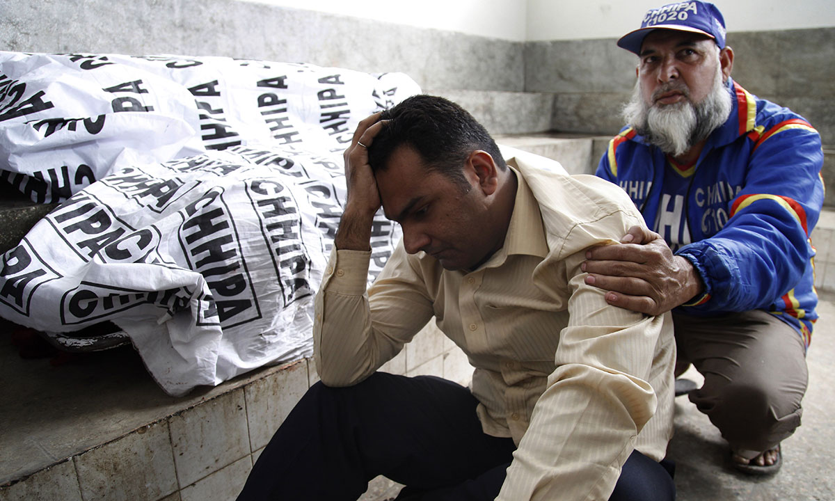 A Pakistani volunteer comforts a man whose wife was killed by unknown gunmen in Karachi, Pakistan. – Photo  by AP