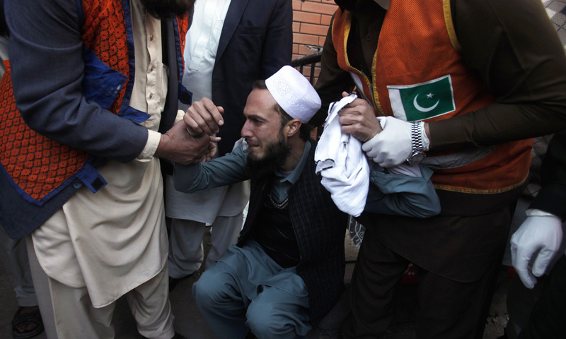 Rescue worker comfort a man over the death of his brother who died in a grenade attack at the Lady Reading Hospital in Peshawar February 11, 2014. – Reuters Photo