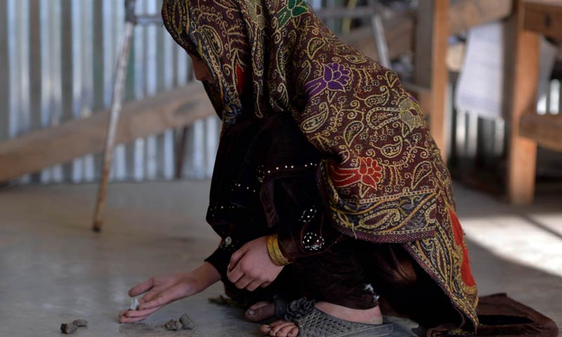 In this photograph taken on Dec 12, 2013, young Pakistani girl Saneeda, who escaped a forced marriage under a local custom of Swara, plays a local game in the Madyan valley of Swat, in the country's northwest. — AFP