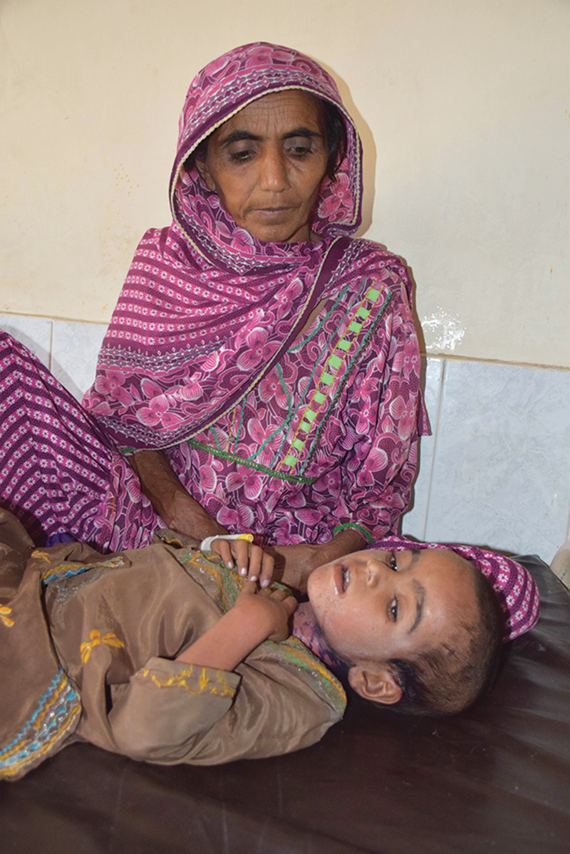 Malka (top) struggles with  measles with her grandmother (right) keeping a watch over her to ensure Malka does not scratch the rash. Another  young man n the same village (below) lies under a neem tree, in the hopes of getting better 