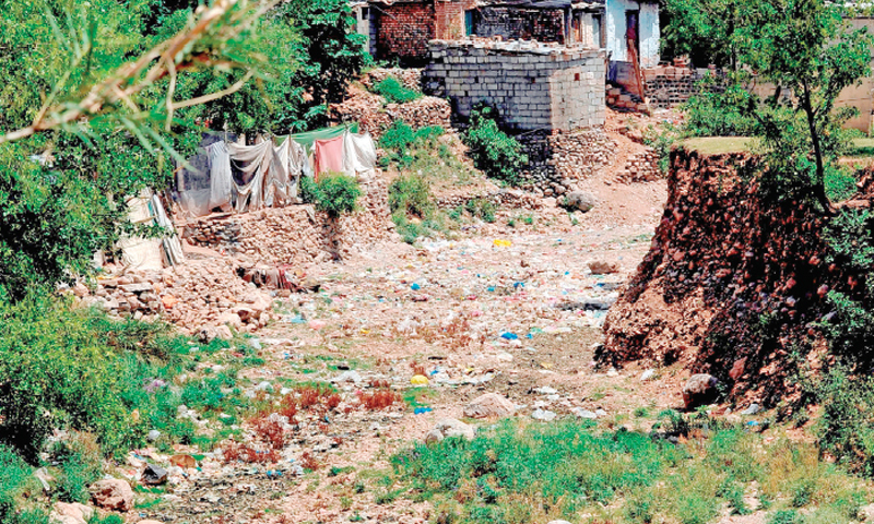 3. This photograph shows the dry bed of one of the storm water drains behind the Prime Minister’s House, situated on a mound on the edge of Noorpur Shahan. Domestic waste of the houses of ordinary people dumped in the dry ground turns it toxic and, when the rains come, it flows downstream. 