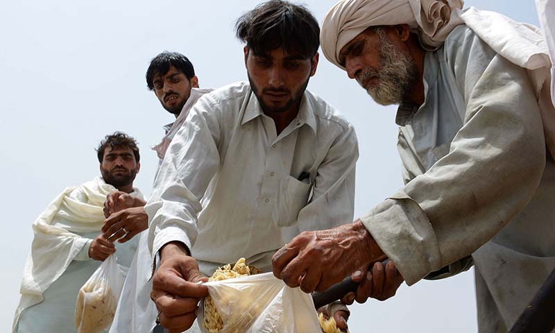 Civilians, fleeing from a military operation in North Waziristan tribal agency, receive food at the Bannu Frontier Region registration centre for internally displaced people in Saidgai on June 22, 2014. — Photo by AFP