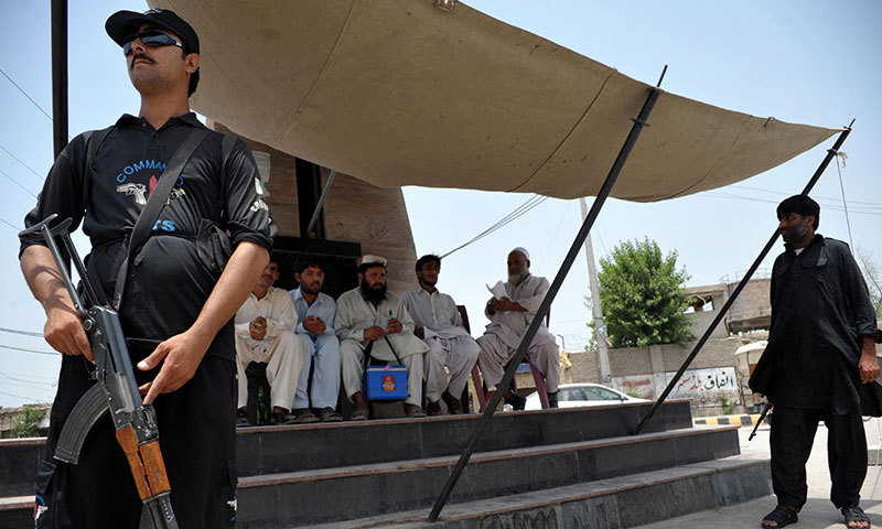 Pakistani police commandos guard a polio vaccination team at a security checkpoint in Bannu on June 26, 2014. — Photo by AFP