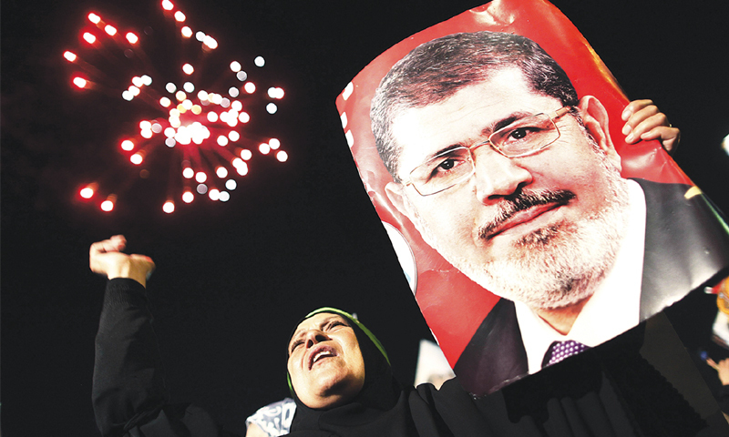 A woman holds a portrait of Mohammed Morsi, Egypt’s first democratically elected president ousted last year, at a rally in Cairo.—AFP