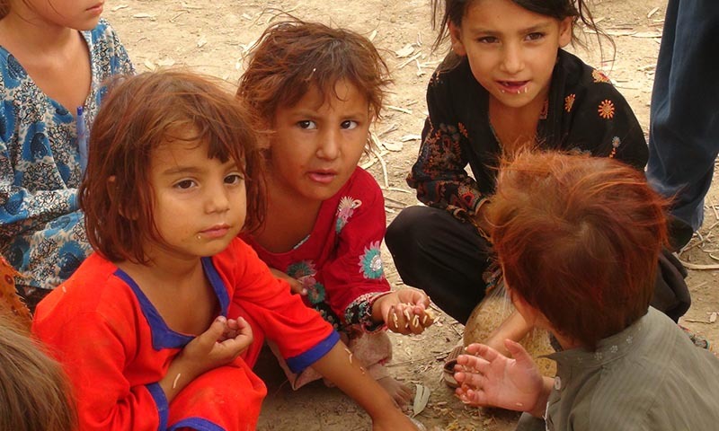 IDP children sit on dirt while sharing a meal.— Photo by Zahir Shah