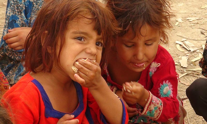 A young girl eats the meal provided at  relief camp in Bannu. — Photo by Zahir Shah Sherazi