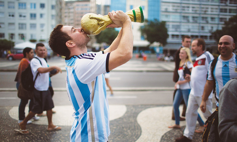Rio de Janeiro: An Argentina supporter kisses a replica of the World Cup trophy at the Copacabana beach on the eve of the final.—AP