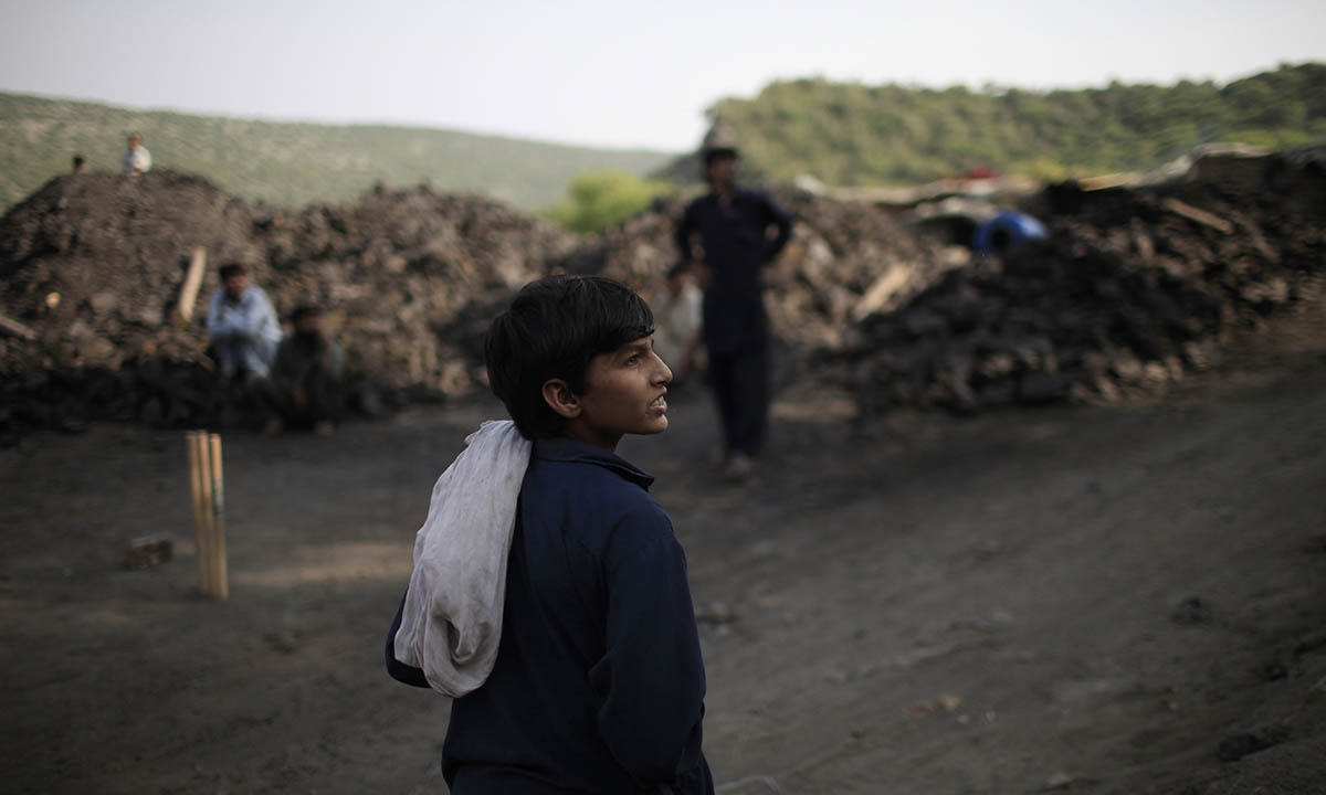 Samiullah watches the other miners play cricket at a coal field in Choa Saidan Shah, Punjab province, May 5, 2014.  — Photo by Reuters