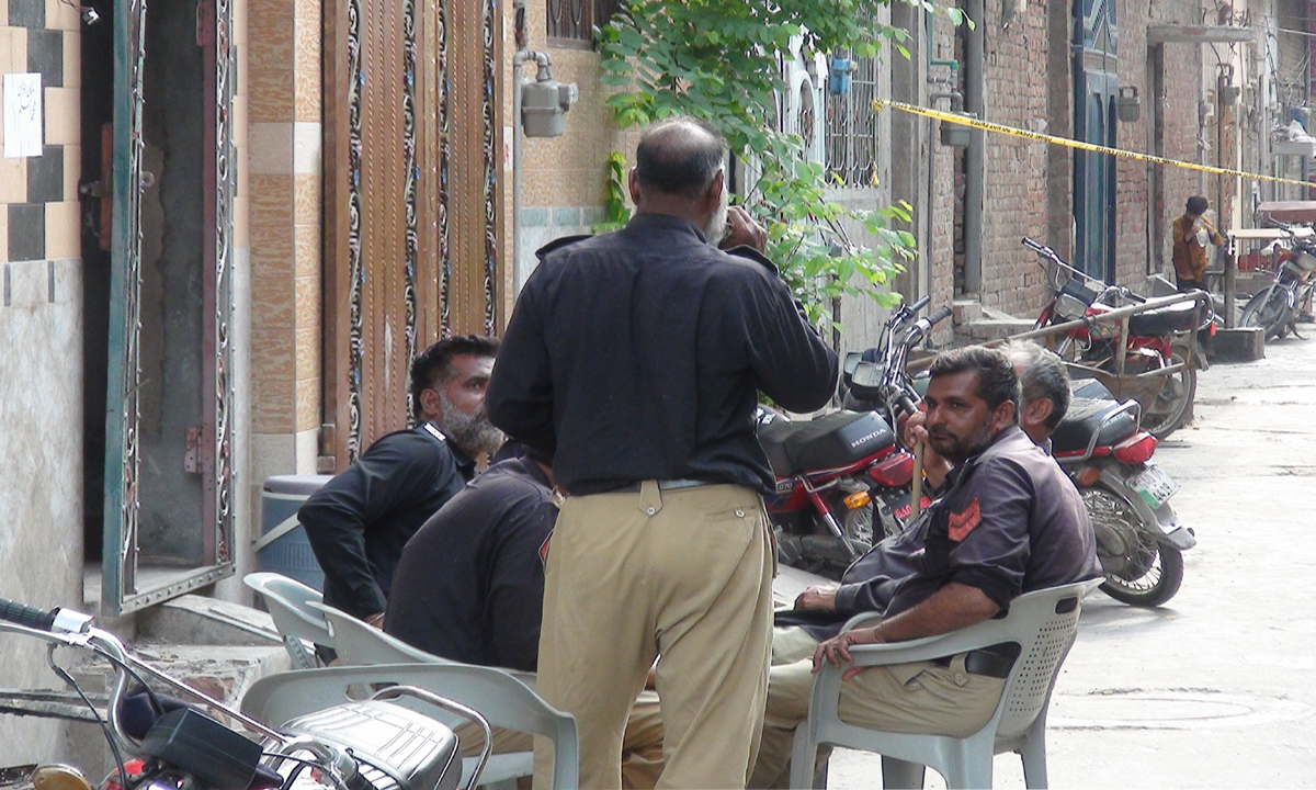 Policemen are deployed outside the torched homes of Ahmadis living in People's Colony