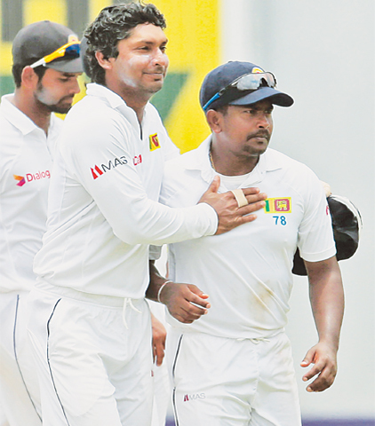 Sri Lankan spinner Rangana Herath (R) is congratulated by team-mate Kumar Sangakkara for his nine-wicket haul on the third day of the second Test.—AP