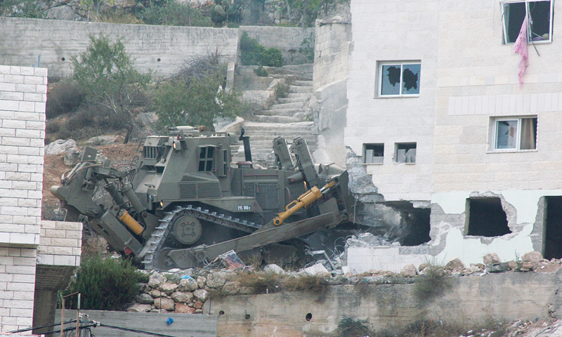 An Israeli army bulldozer destroys the house of Palestinian Zakaria Al-Aqra, 24, after he was killed by the Israeli army in the West Bank village of Qabalan, Nablus. &mdash;Photo by Ahmed Al-Bazz/ActiveStills