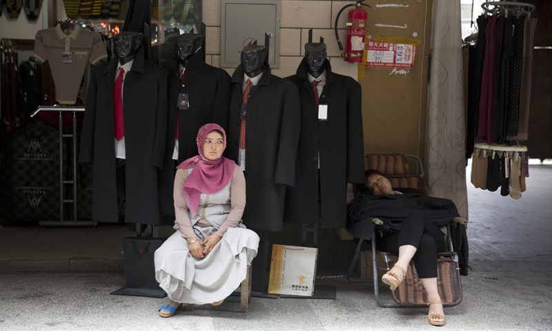  A Uighur woman waits for customers near a Han Chinese woman at a market in the city of Aksu in western China