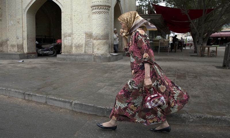 A Uighur woman walks past a mosque in the city of Kuqa in western China