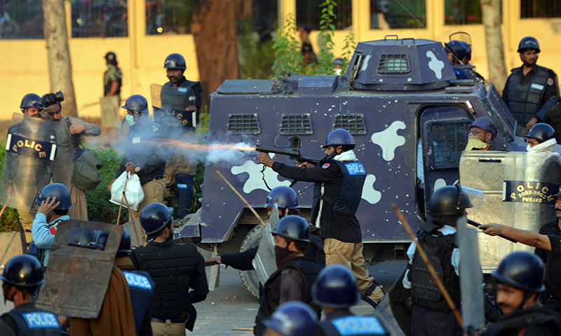 A policeman (C) fires a tear gas shell toward supporters of Imran Khan and Canadian cleric Tahir ul Qadri during clashes near the prime minister's residence in Islamabad on August 31, 2014. — AFP