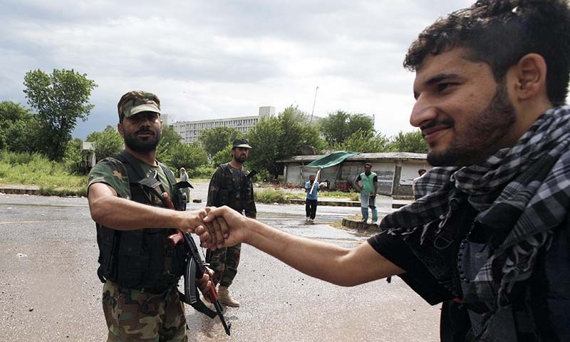 A supporter (R) of PAT chief Tahirul Qadri, shakes hands with a soldier from the Pakistan Army, during the Revolution March towards the prime minister's house in Islamabad September 1, 2014.— Photo by Reuters