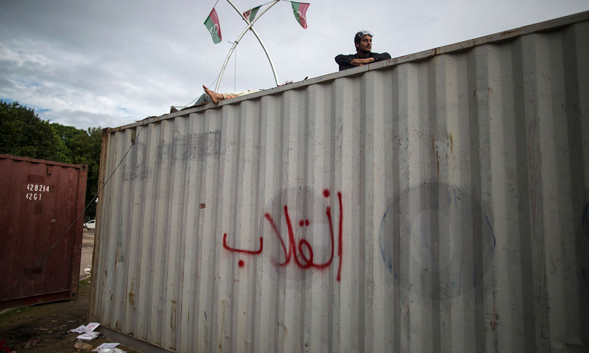 An anti-government protester sits atop a container while his fellow protester sleeps, in front of the President House, Islamabad, Sept 3, 2014. — Photo by Reuters