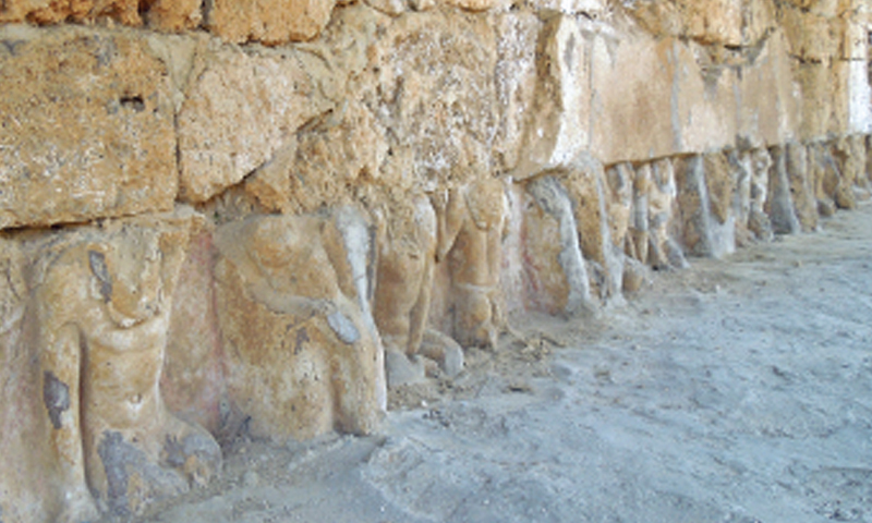 The disfigured statues of Buddha on the outer wall of a medium-size stupa.