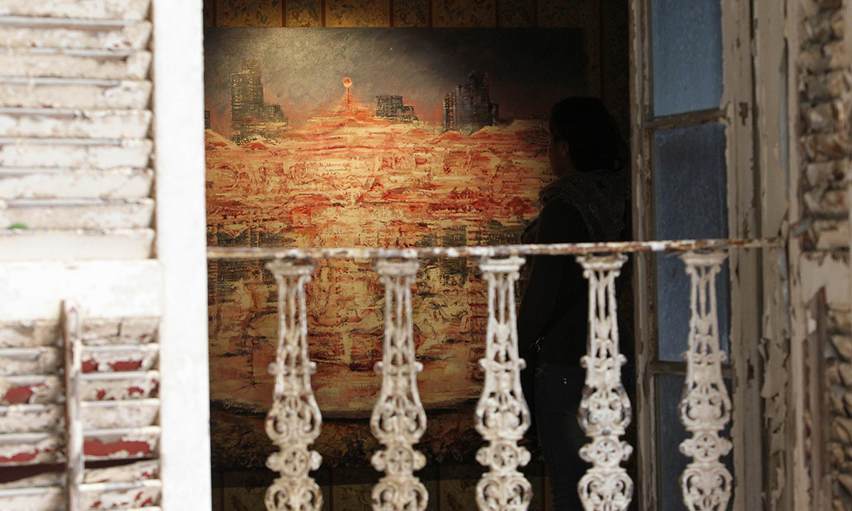 In a picture taken on November 24, 2014, a woman looks at a  painting by British artist Tom Young during an exhibition in Ras Beirut's landmark Rose House. &mdash; AFP