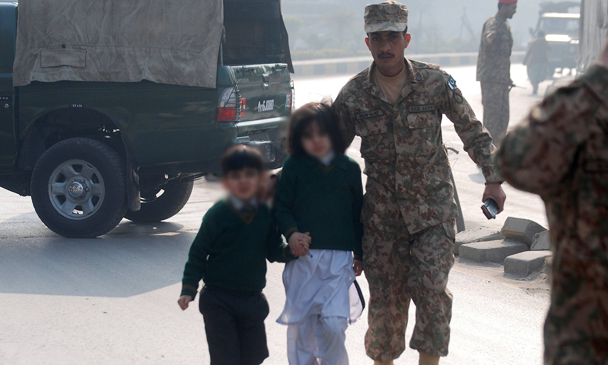 A soldier escorts schoolchildren after they were rescued from the Army Public School. — Reuters