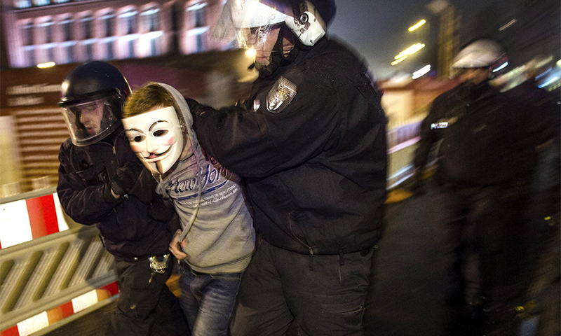 An anti-Pegida-protester wearing a Guy-Fawkes-mask is arrested by the police for refusing to leave the street during a demo against a rally by the mounting right-wing populist movement Pegida on January 5, 2015 in Berlin.--AFP