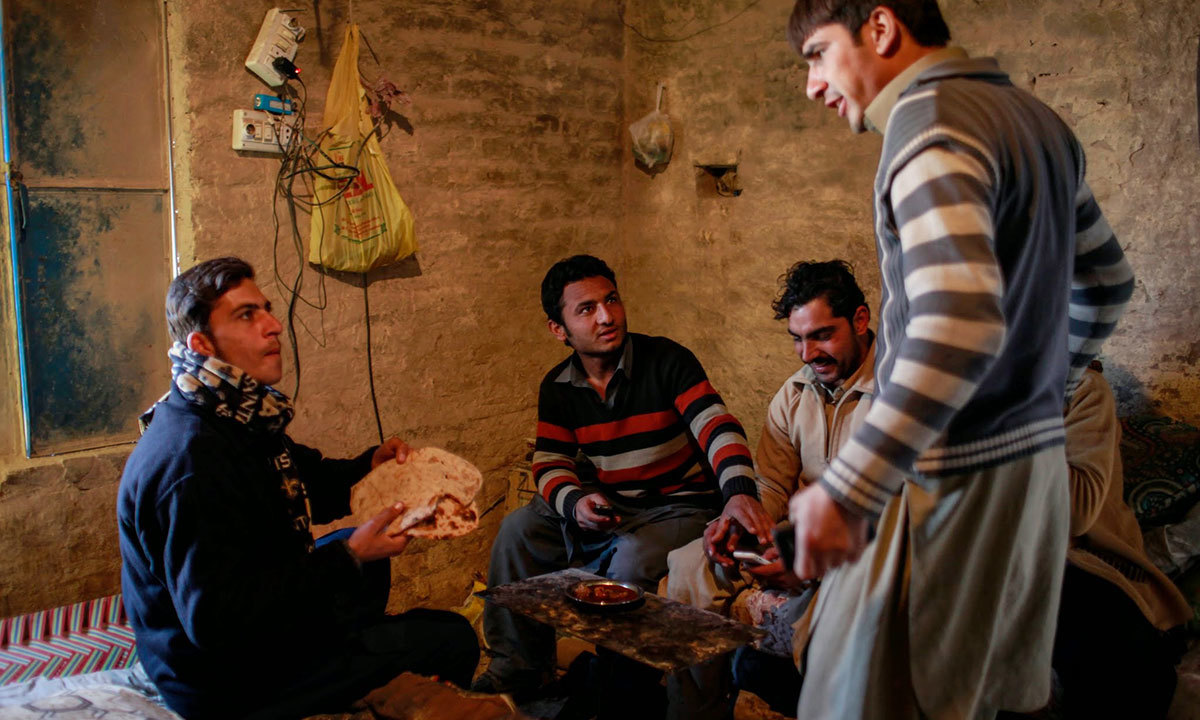 A group of labourers sit inside their makeshift housing to break for lunch. Joking about their cooking skills one of them says, &ldquo;We have learned to cook the best meat curry in Pakistan.&rdquo; - Photo by writer