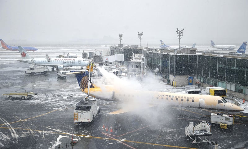 New York: A plane is de-iced at LaGuardia Airport on Monday. Airlines cancelled thousands of flights into and out of East Coast airports as a major snowstorm packing up to three feet of snow barrels down on the region.—AP