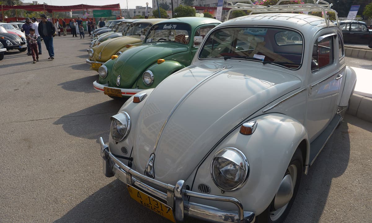 Visitors walk past Volkswagen Beetle cars on display. &mdash; AFP