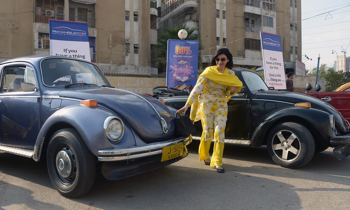 A visitor looks at Volkswagen Beetle cars on display. &mdash; AFP