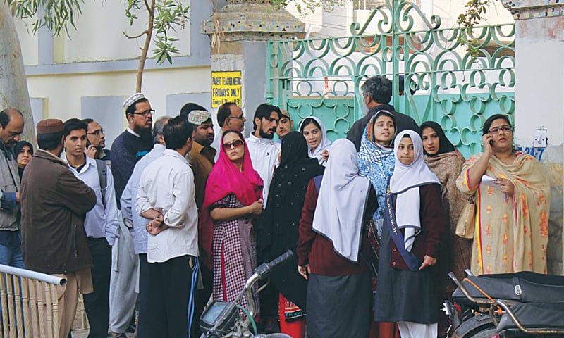 KARACHI: Worried parents and students gathered outside a school after a cracker attack on Tuesday.—PPI