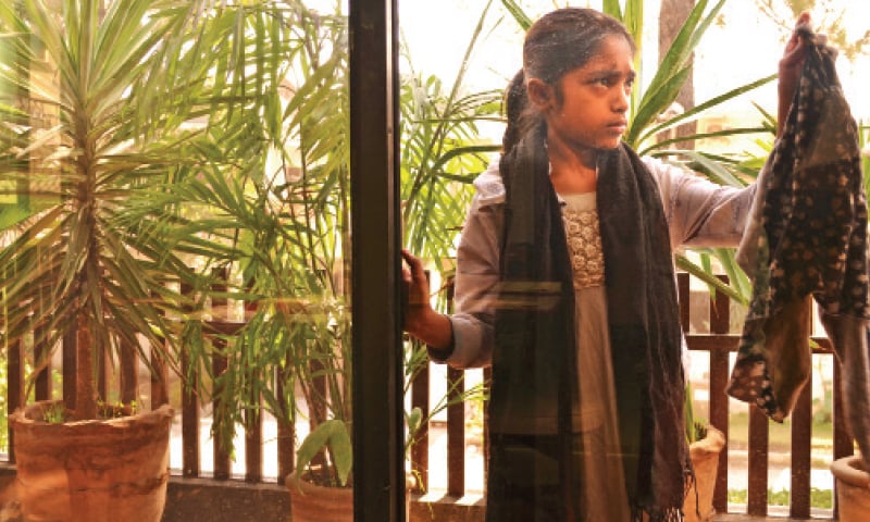 A girl cleans a window at a house where her mother works as a maid. — Photo by the writer