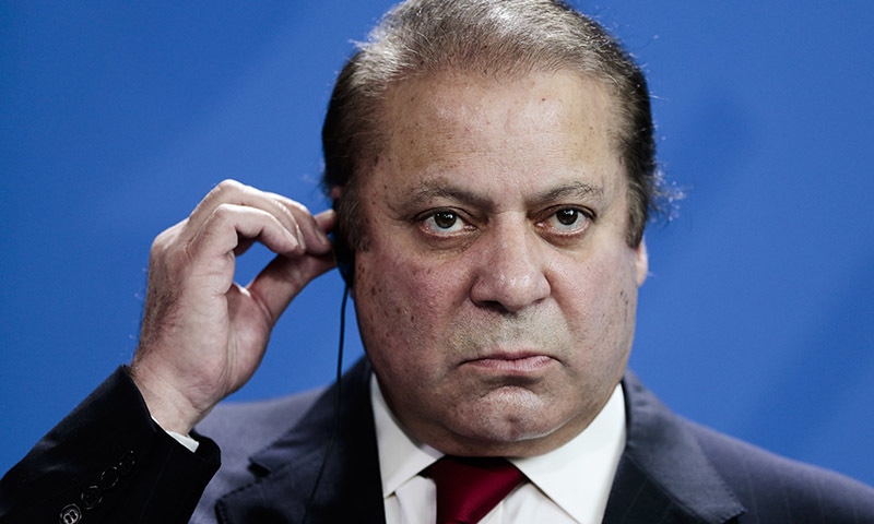 Pakistani Prime Minister Nawaz Sharif holds his ear phone as he attends a news conference. — AP/File