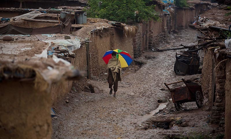 An Afghan refugee boy walks in an alley of a refugee camp in the rain.—AP/File