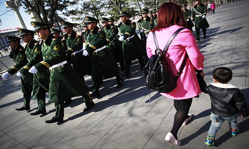 Chinese paramilitary policemen march past a woman and a child near Tiananmen Square in Beijing Wednesday, March 4, 2015 - AP Photo/Andy Wong