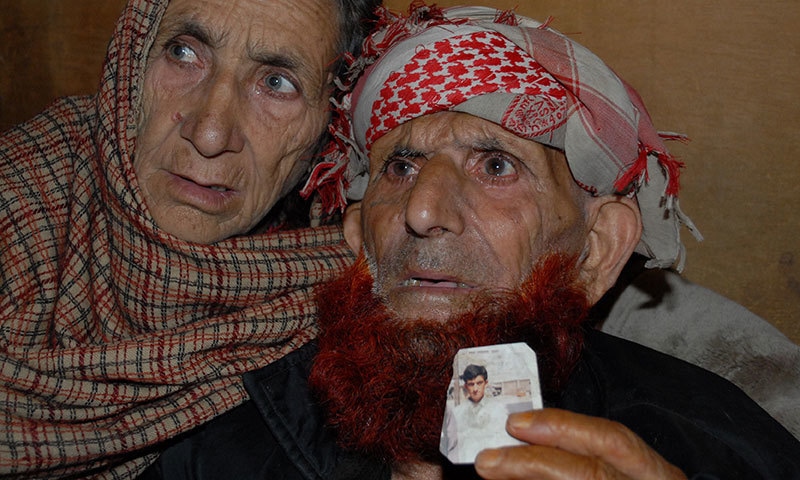 This photograph taken on March 12, 2015 shows the Pakistani Kashmir parents of convicted killer Shafqat Hussain, displaying a photograph of their son, in Muzaffarabad. — AFP