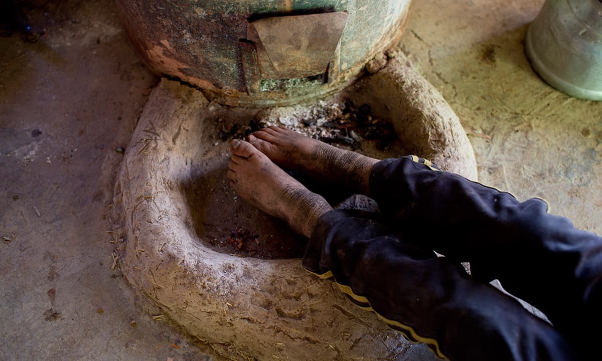 A boy warms his feet by a fire in Ait Sghir village.