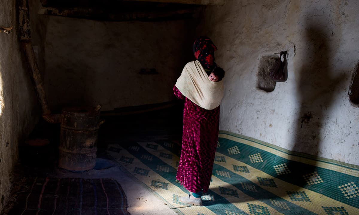 Bari Moumouch, a 20-year-old Berber mother, walks with her baby on her back in the village of Ait Sghir.