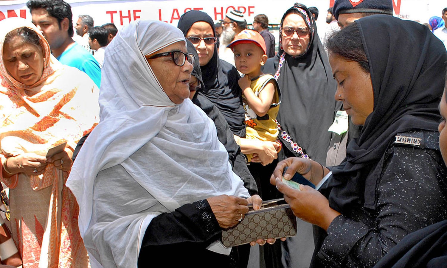 Lady police official checks the NICs of lady voters outside a polling station. Photo by M. Toheed